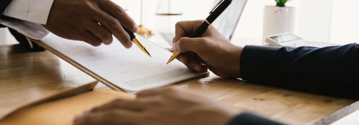 person signing settlement documents with lawyer