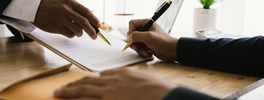 person signing settlement documents with lawyer