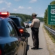 Maryland state trooper conducting a summer traffic stop on Route 50 near Route 301 with police lights flashing and Ocean City highway signs visible.