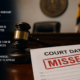 Court date notice stamped “MISSED” on a courtroom desk beside a judge’s gavel, illustrating the legal consequences of missing a court appearance in Maryland.