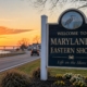 Welcome sign for Maryland’s Eastern Shore beside a coastal highway at sunset, symbolizing relocation and new resident legal considerations.