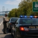 Maryland State Police officer conducting a traffic stop on Route 50 near Centreville with a highway sign for Routes 50 and 301 and the Chesapeake Bay Bridge visible in the distance.